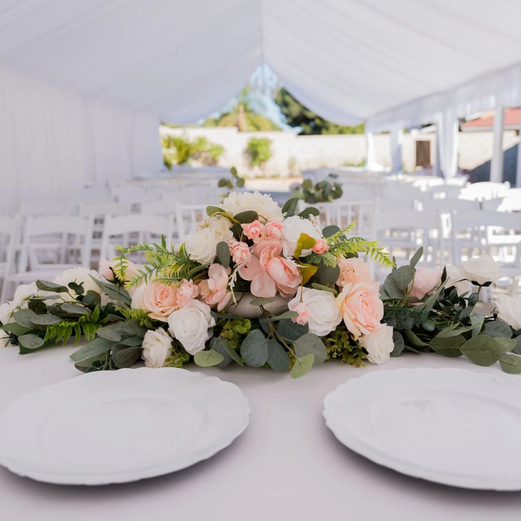 Interior de una carpa de boda con luces cálidas y mesas de madera